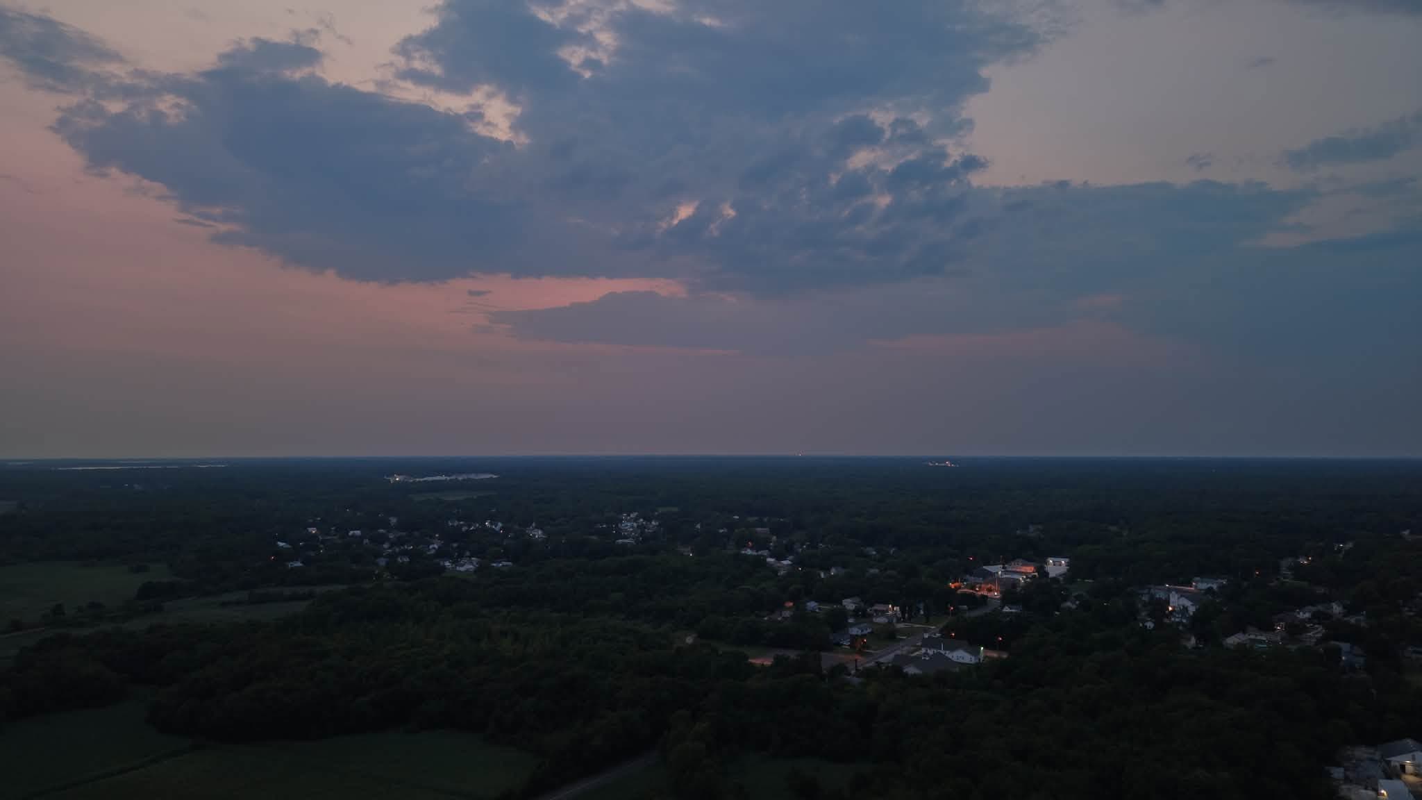 Aerial twilight view of a South Jersey marsh village with lights beginning to glow beneath a pink and blue sky